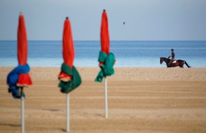 A man rides his horse at a beach in Deauville